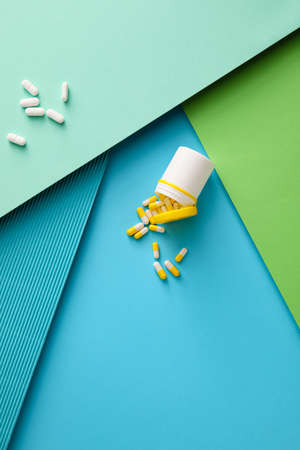 Different capsules with bottle on color background