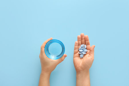 Woman taking pills on blue background, closeupの写真素材