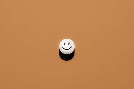 Pill with drawn face on brown backgroundの写真素材