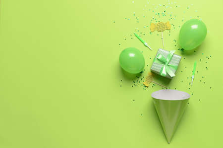 Composition with gift box, balloons, party hat and confetti on color backgroundの写真素材