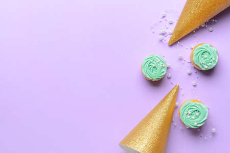 Composition with tasty cupcakes and party hats on color background