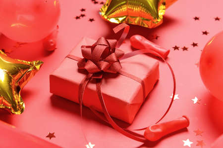 Gift box, balloons and confetti on color background, closeup