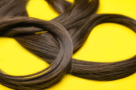 Strands of brown hair on color background, closeup