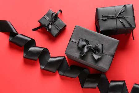 Black gift boxes and ribbon on color background