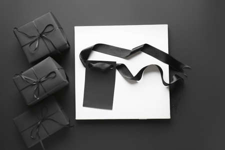 Black gift boxes, tag and card on dark background