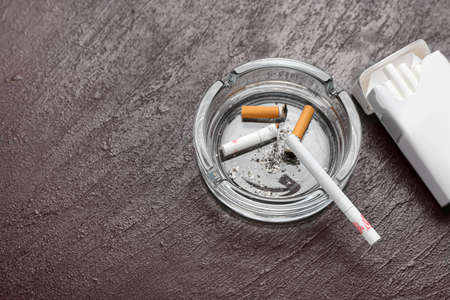 Pack of cigarettes and ash tray on dark background