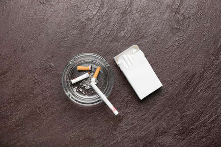 Pack of cigarettes and ash tray on dark background