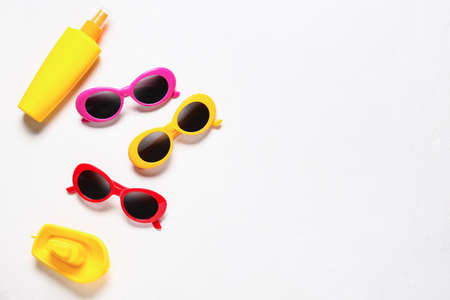 Stylish sunglasses, bottle of sunscreen and toy boat on white background