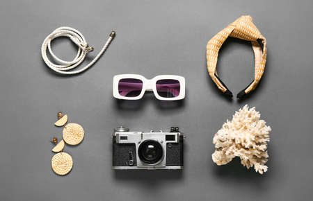 Stylish sunglasses, photo camera and female accessories on dark background
