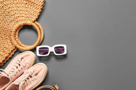 Stylish sunglasses and female accessories on dark background