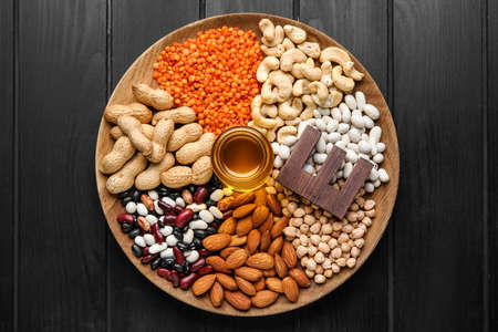 Plate with fish oil and different healthy nuts rich in vitamin E on dark wooden background