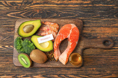 Board with healthy products rich in vitamin E and fish oil capsules on wooden backgroundの写真素材