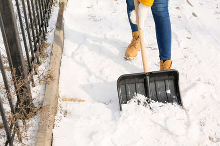 Young woman removing snow outdoors on winter dayの写真素材