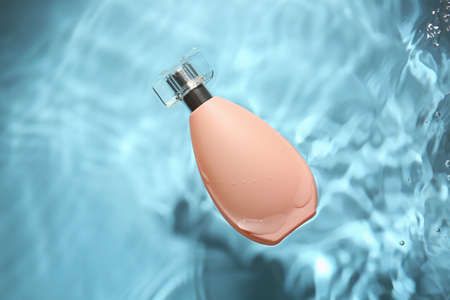 Bottle of aromatic perfume in water on color backgroundの写真素材