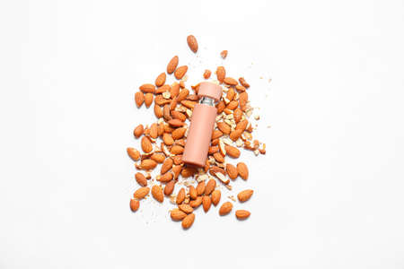 Bottle of perfume and almond nuts on white backgroundの写真素材