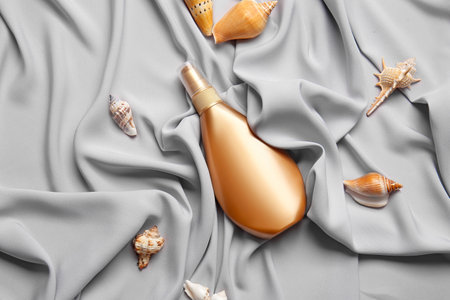 Bottle of cosmetic product and seashells on gray fabric backgroundの写真素材
