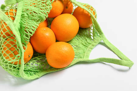 Fresh oranges in eco bag on white background