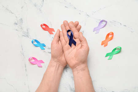 Male hands with different awareness ribbons on light background