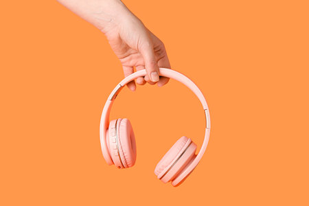 Hand with modern headphones on color backgroundの写真素材