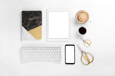 Composition with cup of coffee, mobile phone, tablet computer, keyboard and scissors on white...