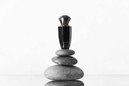 Bottle of perfume and spa stones on white background