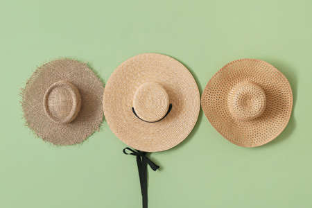 Stylish hats hanging on color wall