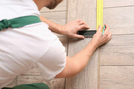 Carpenter taking measurements of laminate flooring in room, closeupの写真素材