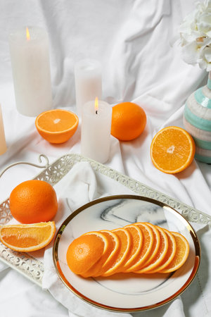 Sliced juicy oranges and burning candles on fabric backgroundの写真素材