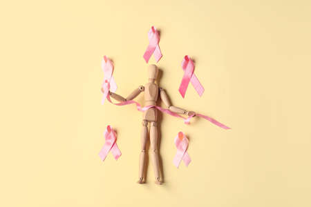 Wooden mannequin with pink ribbons on color background. Breast cancer conceptの写真素材