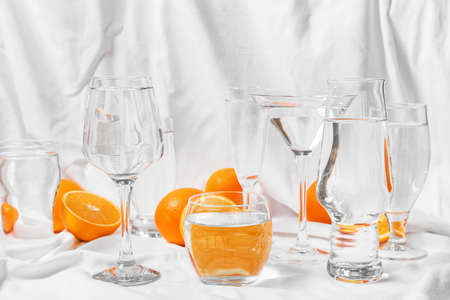 Juicy oranges and glasses of water on fabric backgroundの写真素材