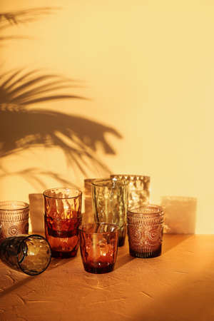 Beautiful empty glasses on table against color wall in roomの写真素材