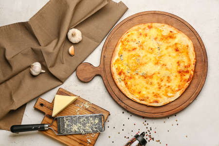 Board with tasty cheese pizza on light backgroundの写真素材