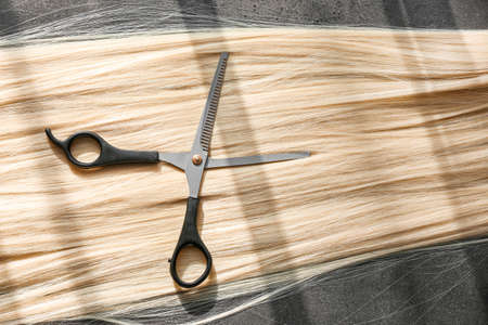 Beautiful blonde hair and scissors on grunge backgroundの写真素材