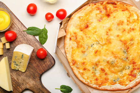 Box with tasty cheese pizza on light backgroundの写真素材