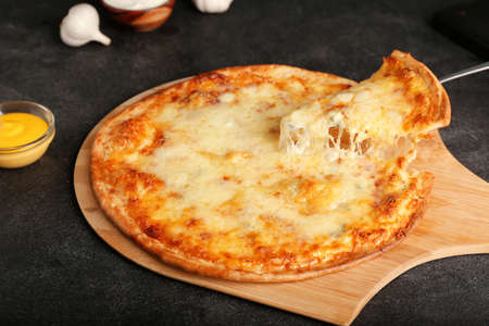 Taking slice of tasty pizza from board on dark backgroundの写真素材