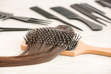Brush with strand of brown hair on table, closeup