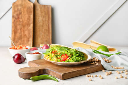 Board with tasty vegetarian taco and sauce on light backgroundの写真素材