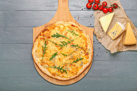 Board with tasty cheese pizza on color wooden background