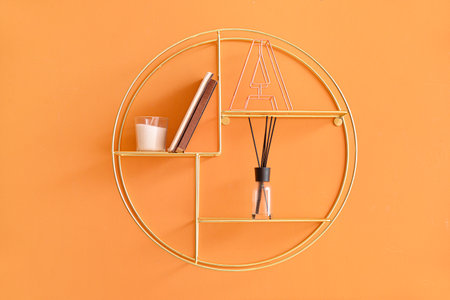 Modern shelf with books and decor hanging on color wallの写真素材