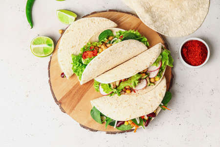 Board with tasty vegetarian tacos on light backgroundの写真素材