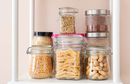 Jars with different products on shelf near color wallの写真素材
