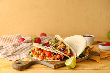 Board with tasty vegetarian tacos on color backgroundの写真素材