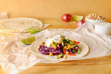 Parchment with tasty vegetarian taco on wooden backgroundの写真素材