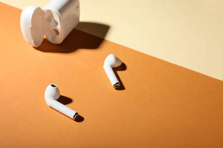 Modern earphones with case on color background, closeup