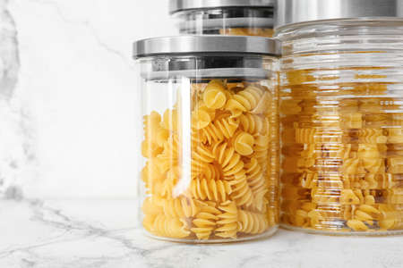 Glass jars with raw pasta on light background, closeupの写真素材