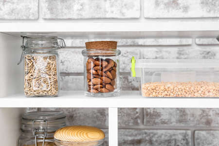 Jars and container with different products on shelves near brick wallの写真素材