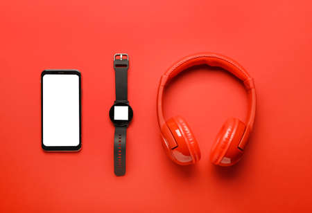 Modern headphones with mobile phone and smart watch on color backgroundの写真素材