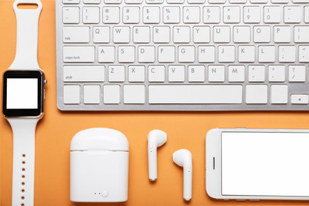 Modern earphones, mobile phone, smart watch and computer keyboard on color backgroundの写真素材