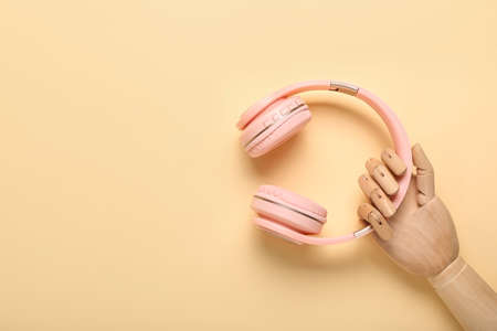 Wooden hand with modern headphones on color backgroundの写真素材