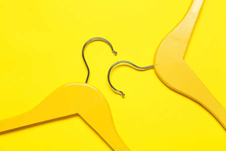 Stylish clothes hangers on color background, closeup